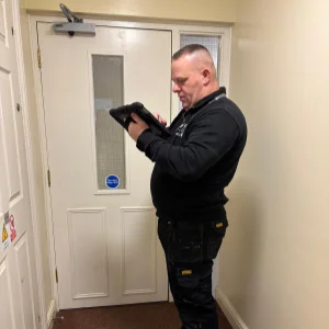 Roy inspecting a fire door with clipboard in hand